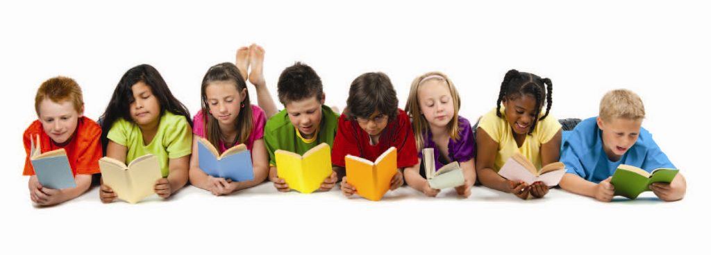 A row of eight children lies on their stomachs against a white background, each reading a book. They wear brightly colored T shirts and hold books in varied colors: light blue, cream, blue, yellow, orange, mint, peach, and green. The children are close together and focused on the pages, creating a cheerful, studious scene. No other objects or background details are present.