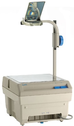 A beige overhead projector on a plain white background. The boxy base has a clear glass stage on top for transparencies, small vents, and a front panel with a pull out section. A vertical arm rises from the rear, featuring a large blue focusing knob. At the top, a hinged projection head contains a lens and an angled mirror to direct the image forward. A power cord loops from the back. The device appears clean and functional.